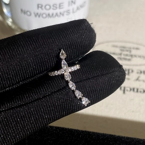 Macro view of silver cross ring with pear-cut cubic zirconia stones on black glove