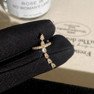 Macro shot of gold cross earring with marquise cubic zirconia on black glove