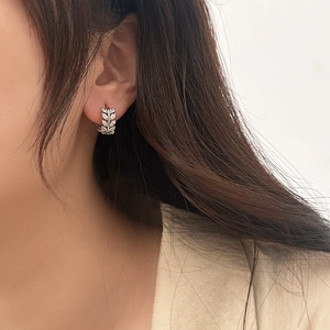 Detail of elegant leaf earrings with sparkling cubic zirconia worn on earlobe