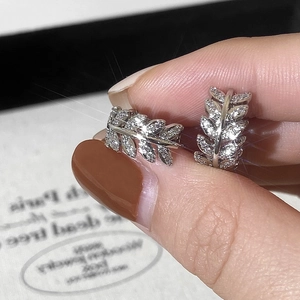 Macro shot of silver leaf-shaped earrings with shimmering cubic zirconia stones inlay