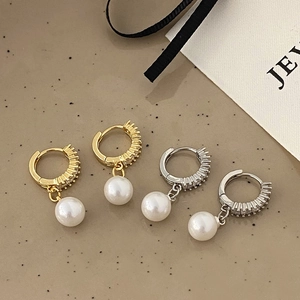 Close-up of gold and silver pearl drop earrings with sparkling zircon inlay details