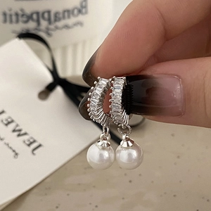 Close-up of elegant pearl drop earrings with rectangular zircon accents and silver finish