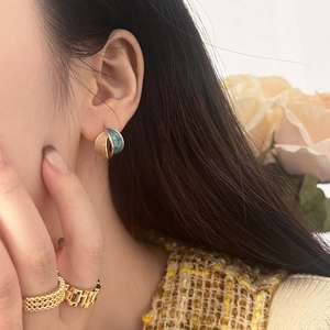 Elegant bi-color enamel leaf earrings in cream and blue with gold plated edges on model