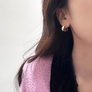 Detail of C-shaped enamel earrings in white and burgundy worn by a model