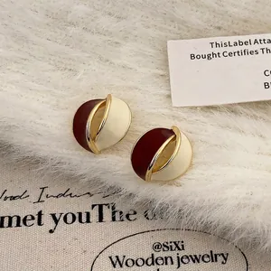 Macro shot of retro gold-plated hoop earrings with burgundy and cream enamel detailing