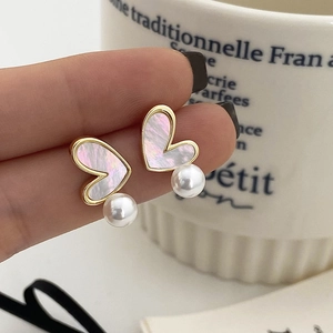 Macro view of heart-shaped earrings featuring shell inlay and round white pearls