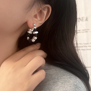 Close-up of irregular silver beads and black stones on a beaded hoop earring