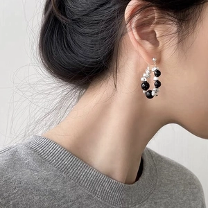 Close-up of elegant beaded hoop earrings with silver and black beads on female model