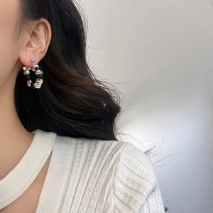 Detail of irregular silver beads and black stones hoop earrings on a model's ear