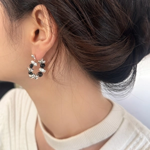 Detail of silver irregular stone and black beads hoop earrings on model ear