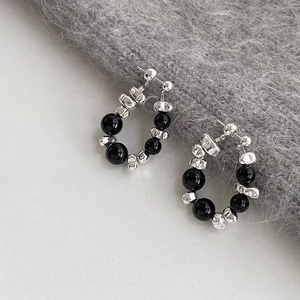 Detail of beaded hoop earrings featuring textured silver nuggets and black resin beads
