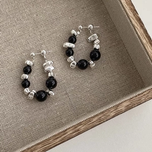 Detailed close-up of C-shaped hoop earrings with silver beads and black polished stones