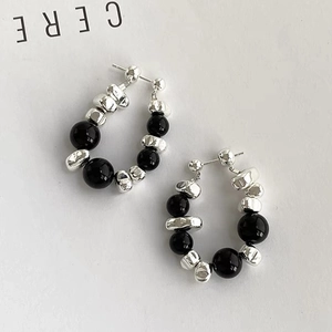 Detail of beaded hoop earrings with black polished beads and irregular silver stones