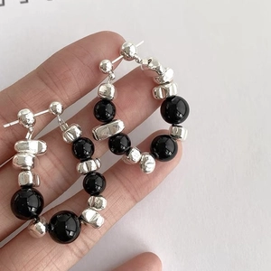 Macro detail of irregular silver nuggets and black beads on elegant hoop earrings