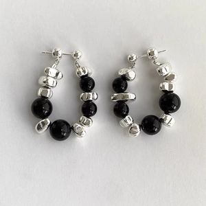 Detailed view of C-shaped hoop earrings with hammered silver beads and black stones