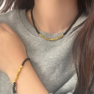 Detail of beaded necklace and bracelet set with black beads and gold-tone spacers