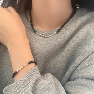 Detail of minimalist black beads and silver square spacers on necklace and bracelet set