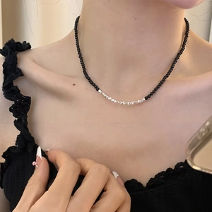 Close-up of minimalist black bead and silver nugget splice necklace on a model