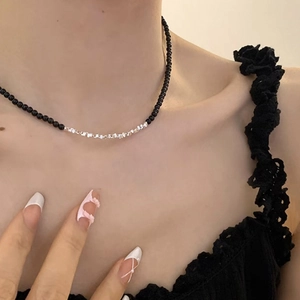 Close-up of a minimalist necklace with black beads and irregular silver metal accents