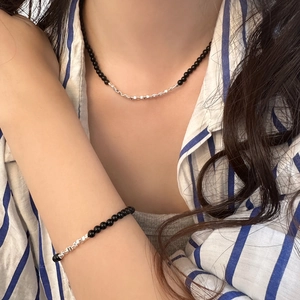 Detail of beaded necklace and bracelet set with black stones and silver metal squares