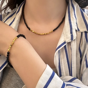 Detailed close-up of a black stone bead necklace and bracelet set with golden cubes