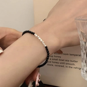 Close-up of beaded bracelet featuring black stones and silver geometric metal accents