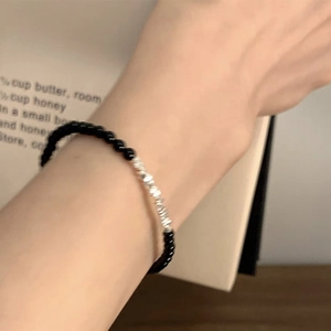 Close-up of beaded bracelet with black round beads and irregular silver metal accents
