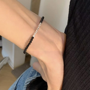 Detailed shot of black beads and silver irregular nuggets on a wrist, minimalist style