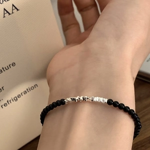 Detail shot of tiny black beads with irregular silver accents on a minimalist bracelet