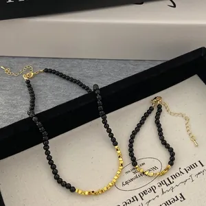 Close-up of black beads and gold square charms on this minimalist necklace and bracelet set