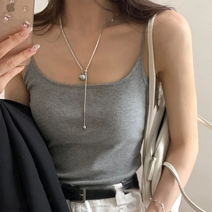 Close-up of a silver lariat necklace featuring a grey pearl pendant and metal tassels
