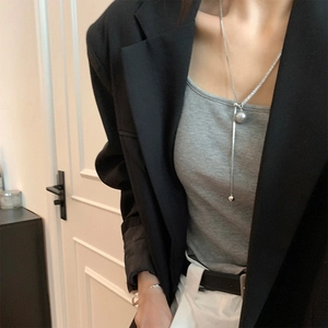 Long Y-shaped silver necklace with zircon tassels worn over a black blazer and grey top