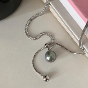 Macro detail of dark grey pearl pendant with zircon-encrusted silver chain and slider