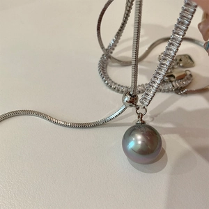 Close-up of elegant dark grey pearl necklace with zircon inlay on silver snake chain