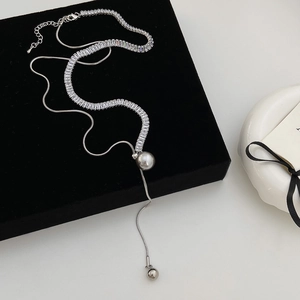 Detailed macro of double-layer silver necklace with zircon band and pearl tassel charms