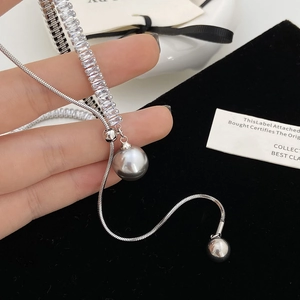 Macro shot of silver snake chain featuring square-cut zircons and grey pearl tassels