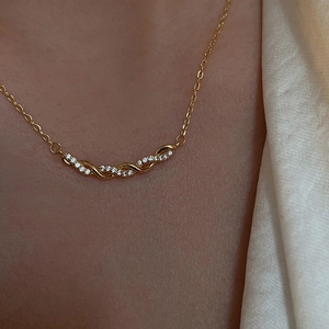 Gros plan du collier avec pendentif torsadé en or et zircon porté sur un modèle élégant