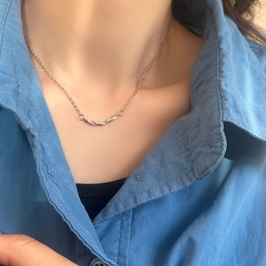 Gros plan du pendentif torsadé argenté avec cristaux sur une chaîne maille forçat