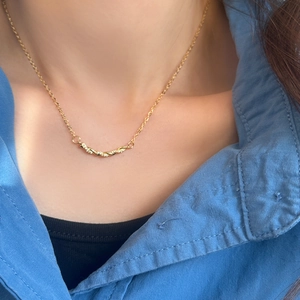 Détail du collier torsadé en or avec pendentif en zircon porté par un mannequin