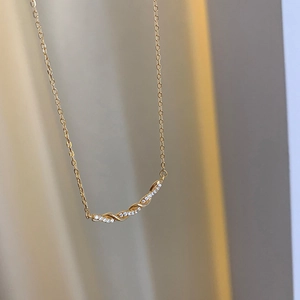 Détail d'un collier torsadé doré orné de zircons brillants et d'une fine chaîne en O