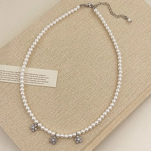 Détail du collier de perles avec fleurs en argent et fermoir mousqueton sur papier rétro