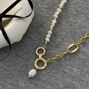 Minimalist freshwater pearl and gold link chain necklace on textured background