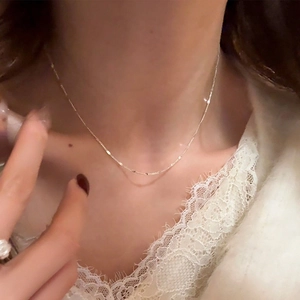 Close-up of a minimalist silver-toned fine link chain necklace worn on the neck