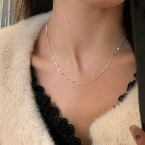 Close-up of minimalist silver chain necklace worn by a model on faux fur background