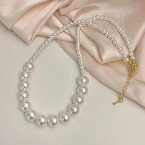 Vue détaillée du collier de perles élégant avec fermoir doré sur tissu en soie champagne