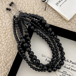 Layered black natural stone beaded necklace with adjustable silver clasp on velvet