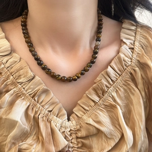 Gros plan d'un collier en perles d'oeil de tigre avec effet oeil de chat sur un mannequin