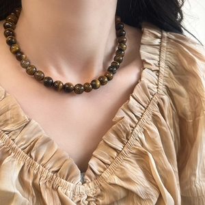 Gros plan d'un collier en pierre œil de tigre naturelle sur cou, style rétro français