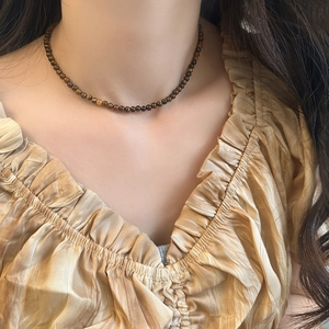 Collier en perles d'oeil de tigre sur cou de femme au style vintage français