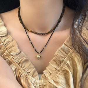 Gros plan d'un collier en œil de tigre avec pendentif cœur doré et perles facettées